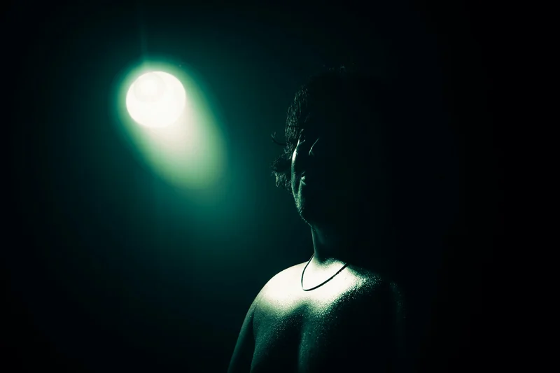 Person im Profil vor einem einzelnen Scheinwerfer