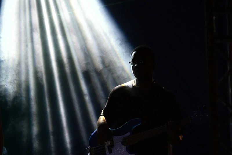 Bassist auf der Bühne zwischen Lichtstrahlen
