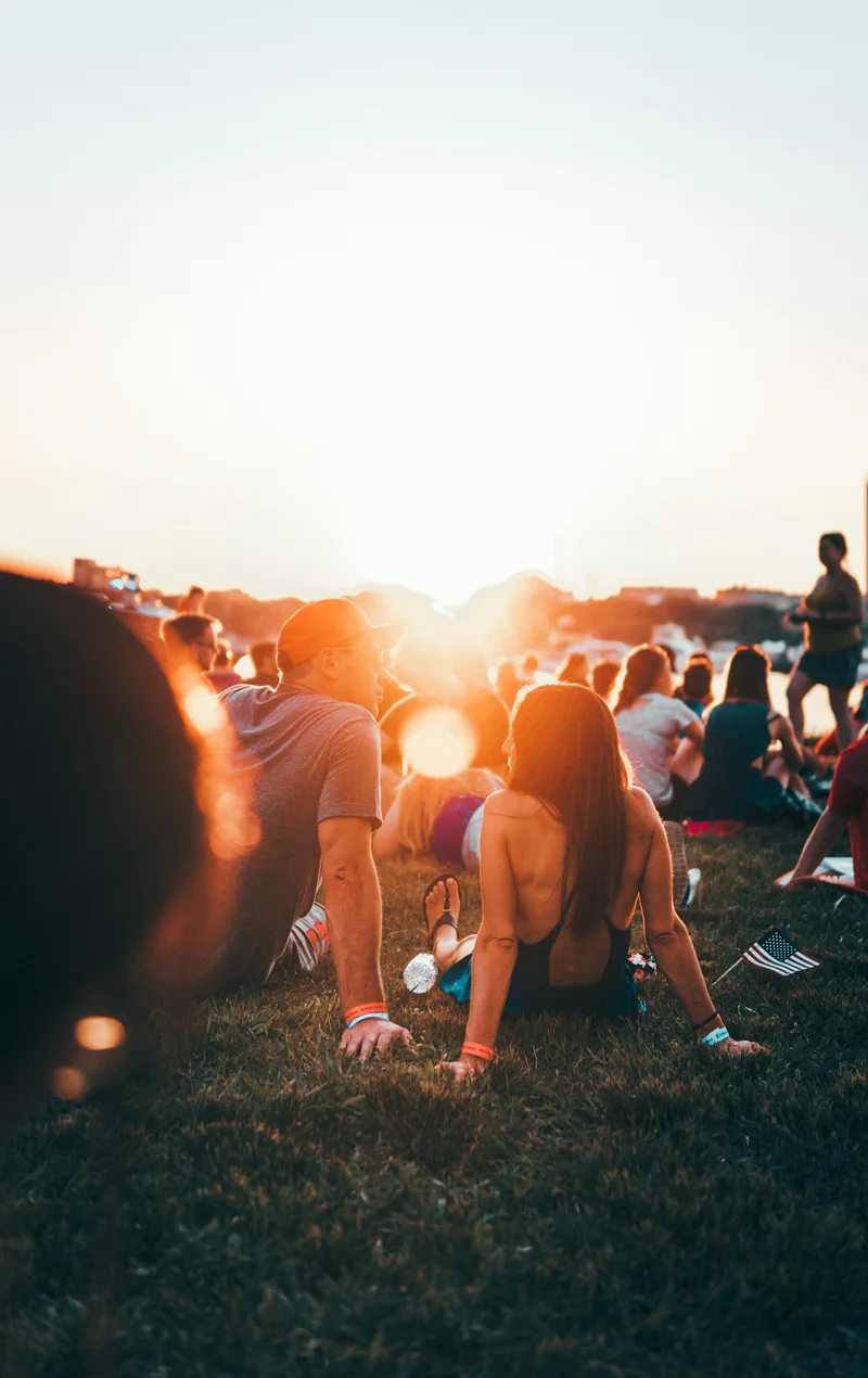Menschen sitzen bei Abendsonne auf einer Wiese