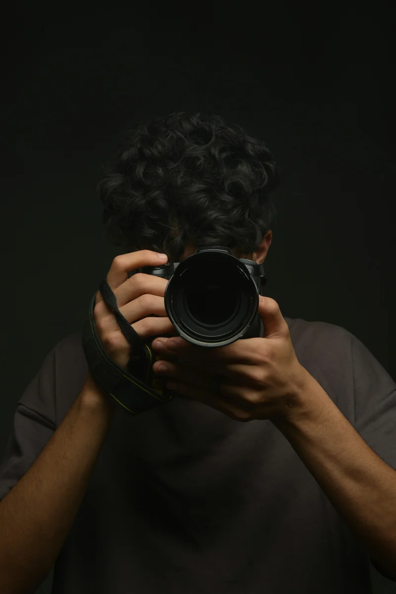 Fotograf hält die Kamera vor sein Gesicht